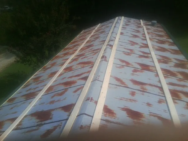 Rusted metal roof panels with new wood purlins before replacement — Storm Damage Roof Repair in Brown City by Roofing Brothers