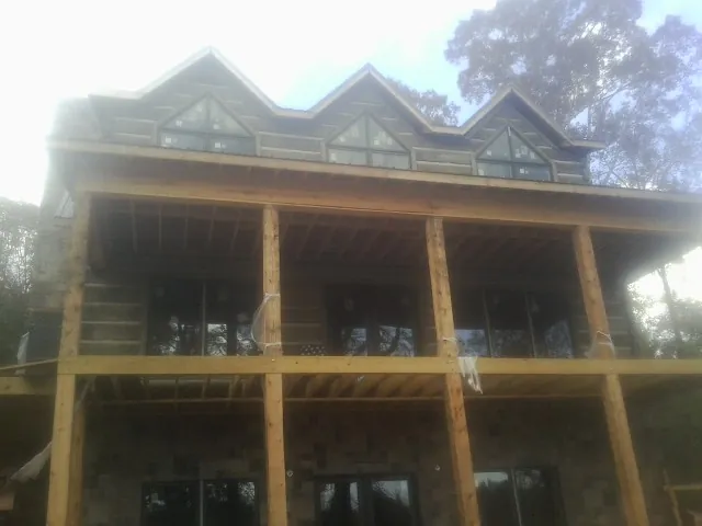 Dormers and porch framing on a large log home under construction — Roof Coating work by our crew in Brown City