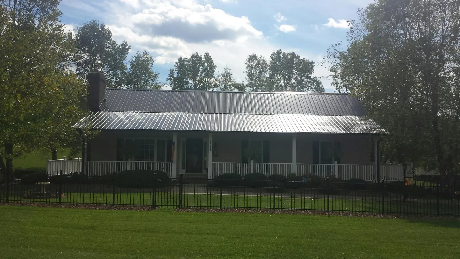 Gray metal roof on a brick ranch with a full width front porch — Gutter Guard Installation work by our crew in Brown City