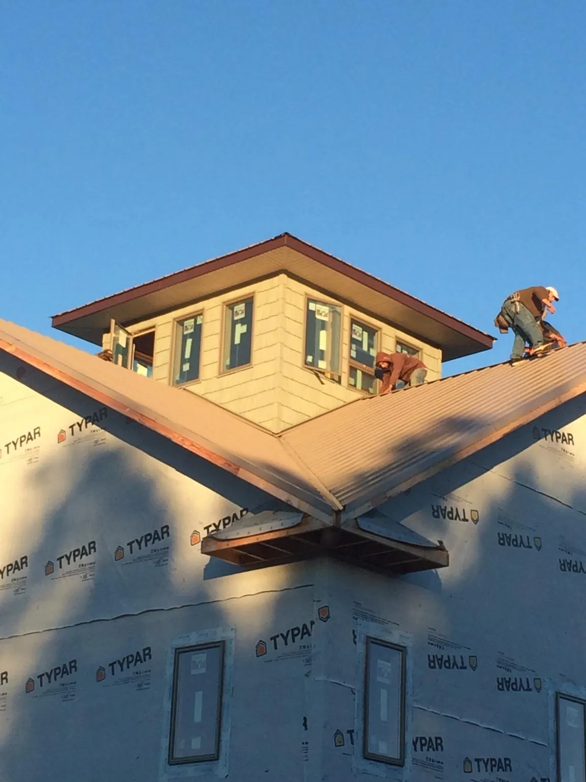 Roofers working around a rooftop cupola on a new metal roof at sunset — Roof Waterproofing in Brown City by Roofing Brothers
